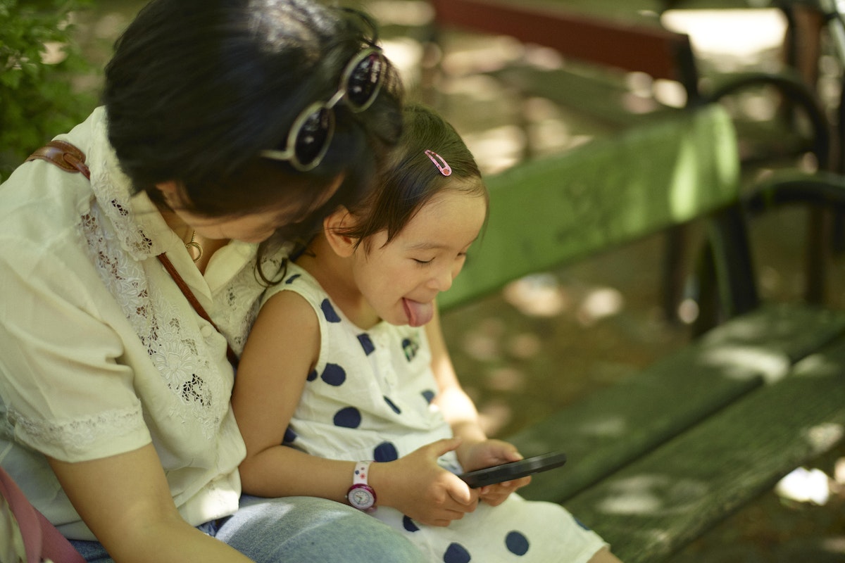 Mother and daughter are sitting on a park bench and using Earth Speaker app